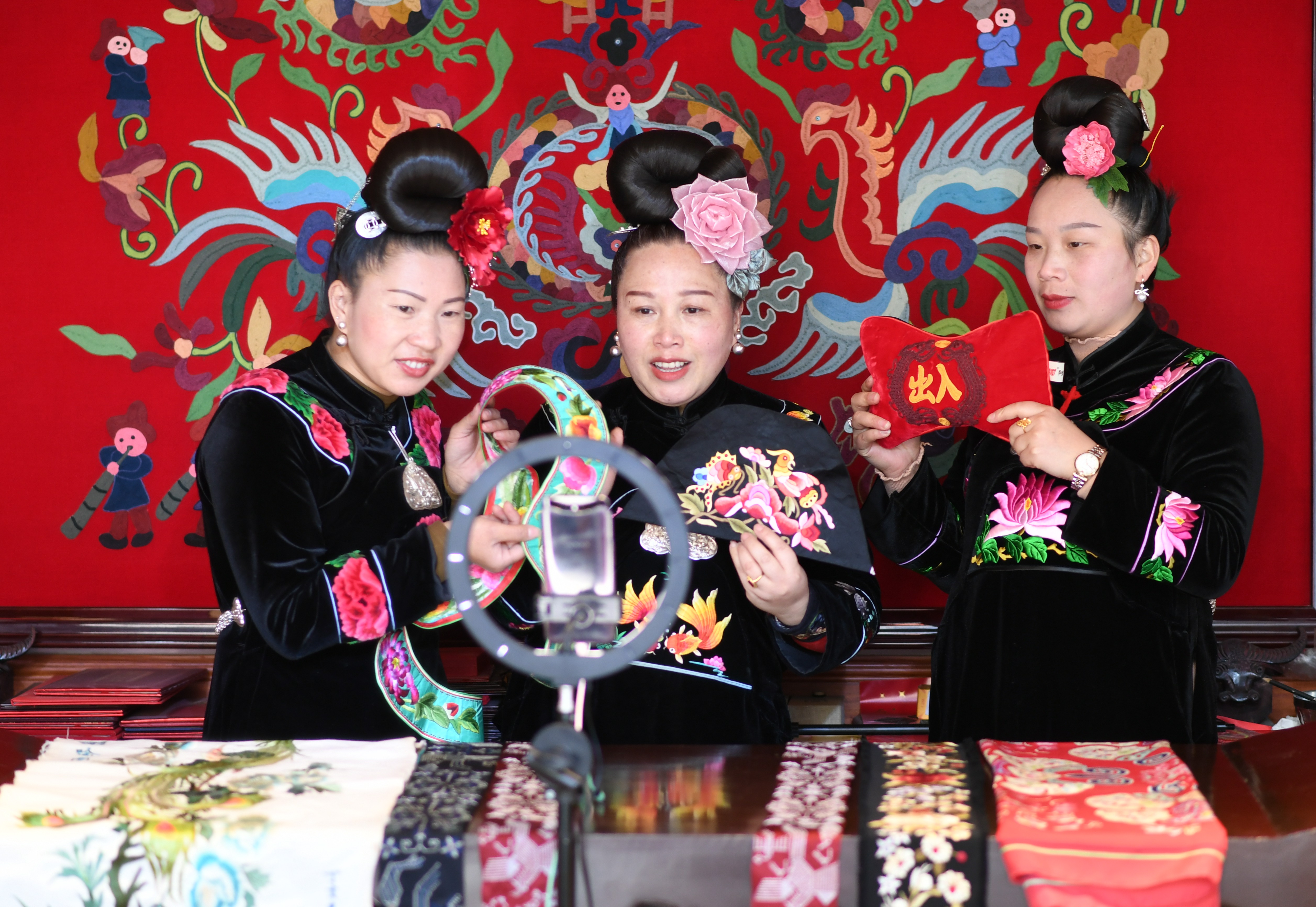 楊阿妮（中）帶兩名繡娘在進行網(wǎng)絡(luò)直播，介紹苗繡產(chǎn)品。陳沛亮攝.JPG