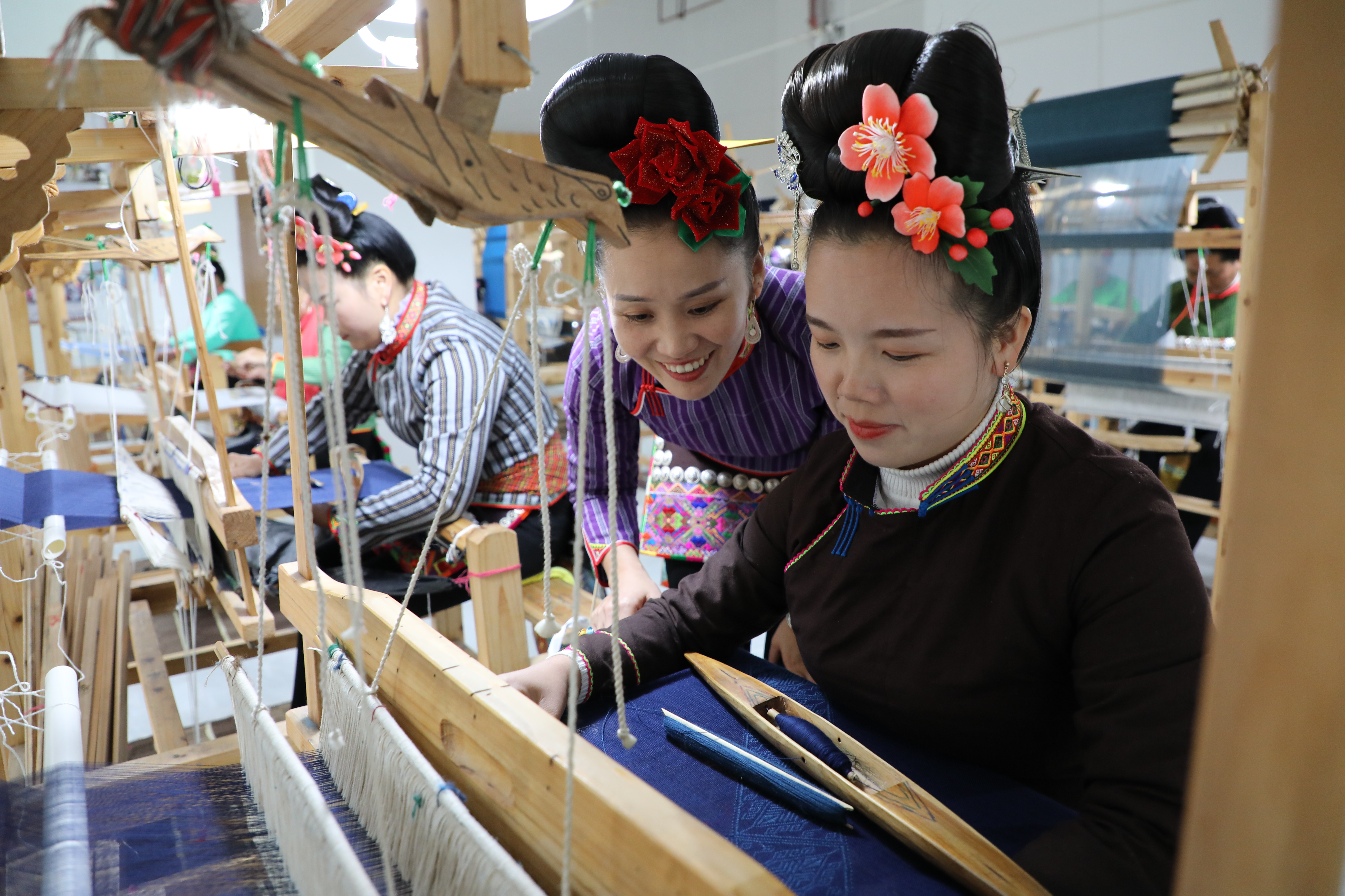 雷山縣龍頭街道錦雞繡業(yè)非遺扶貧就業(yè)工坊，苗族織錦技藝省級(jí)非物質(zhì)文化遺產(chǎn)傳承人甘小芝（左）正在指導(dǎo)繡娘學(xué)習(xí)織錦技藝。楊承鴻攝.JPG