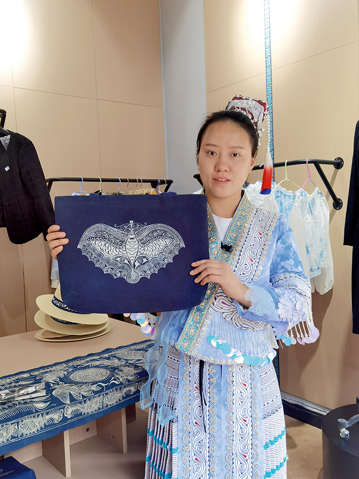 設(shè)計(jì)更多實(shí)用的產(chǎn)品，讓非遺走進(jìn)生活。圖為楊文麗展示工坊生產(chǎn)的蠟染手提袋。.jpg
