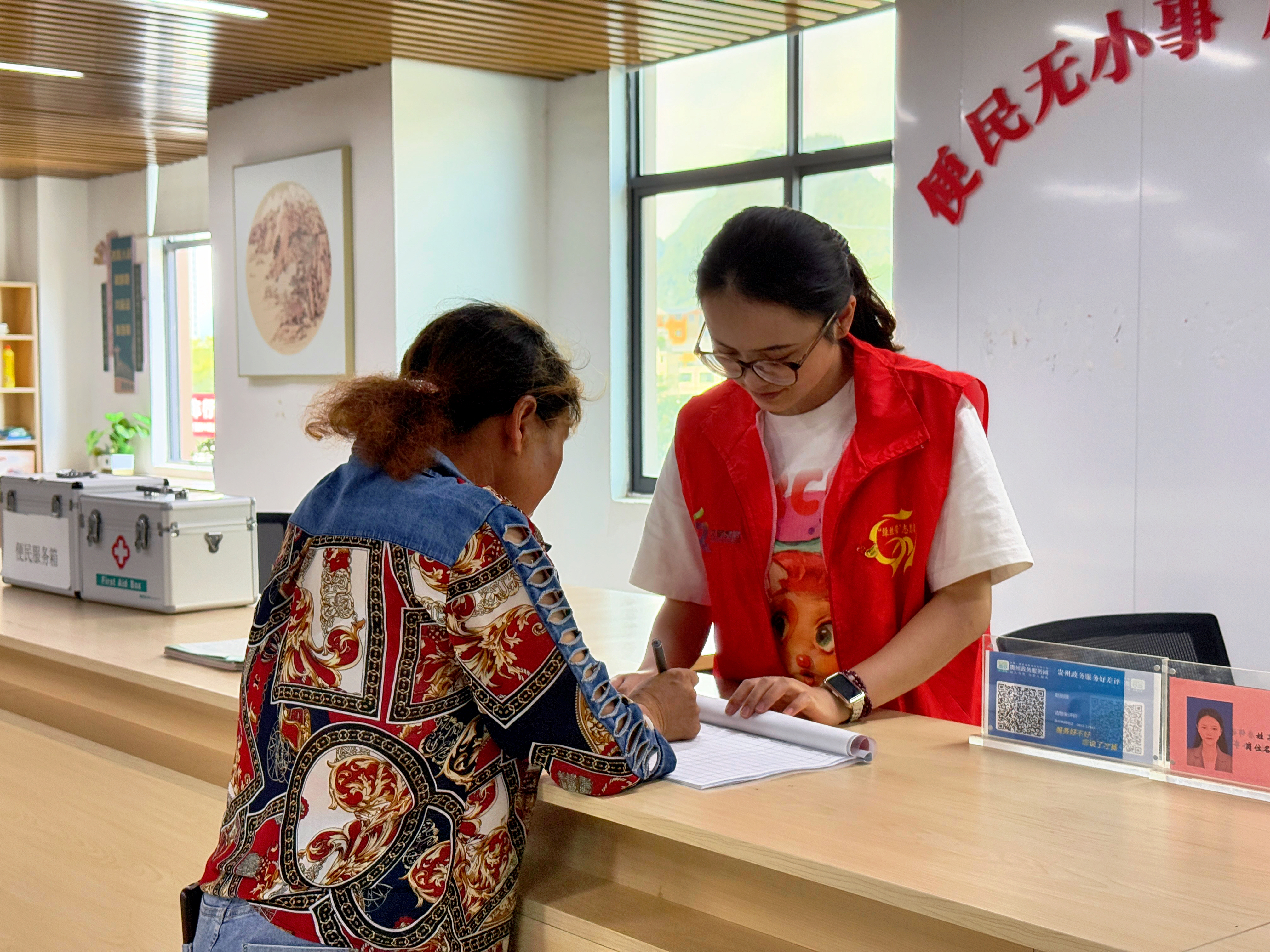 圖為花溪區(qū)孟關(guān)鄉(xiāng)沙坡村黨群服務(wù)中心，工作人員正在為老年人提供補貼辦理服務(wù).jpg