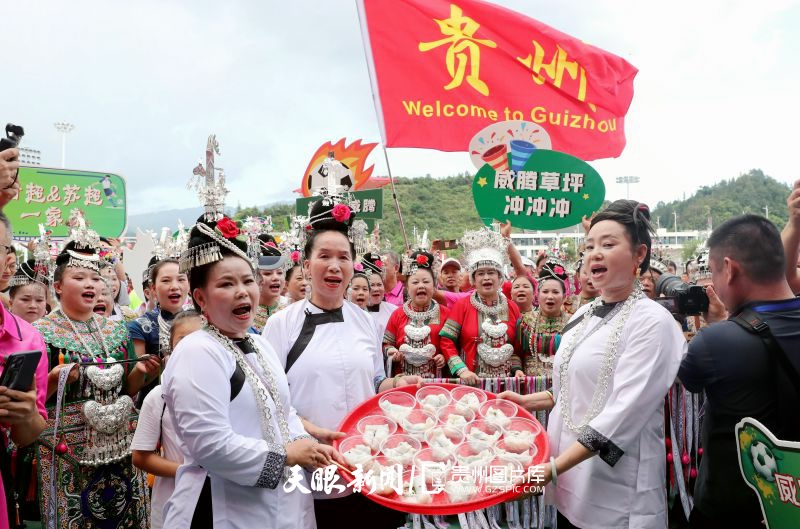 dD0xNzYzNjg5NzM2X3I9OTZkZTFiMGVfdz04MDBfcT0xMDBfZT1qcGc=.webp 图3:2025年7月25日,在贵州省黔东南苗族侗族自治州榕江县城北新区“村超”足球场,当地群众端着特色美食迎接抗洪救援人员回榕江看“村超”。.jpg