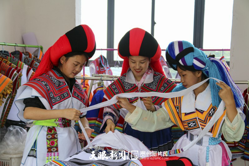 497123-2022年6月25日，苗族妇女在贵州省毕节市纳雍县锅圈岩苗族彝族乡刺绣作坊里，整理刺绣成品腰带。.jpg