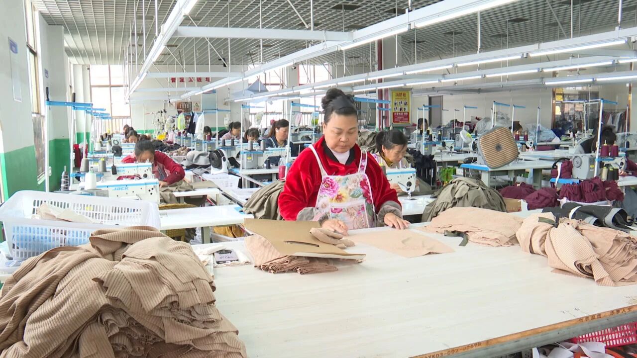 在普定县定南街道鑫旺社区安淇尔服装有限公司，近千平方米的服装加工车间里机声轰鸣，缝纫机、锁边机整齐排列，工人们正专注地赶制一批服装订单。.jpg