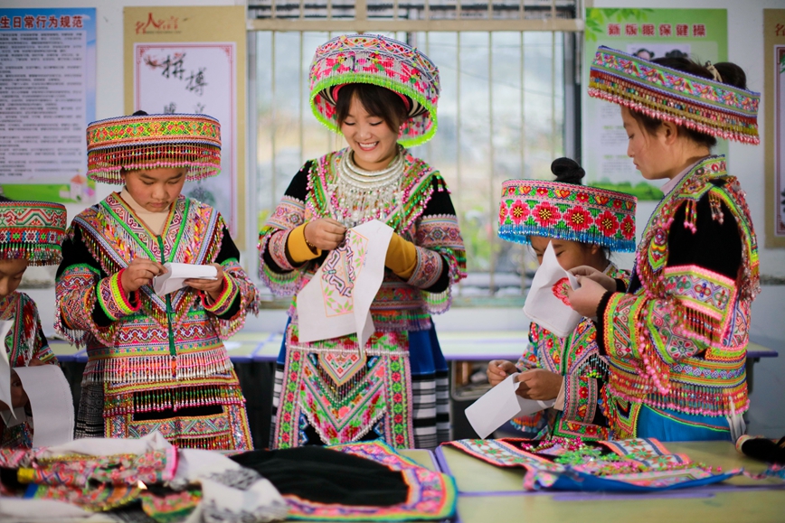 2025年12月16日，贵州省黔西市太来彝族苗族乡院子小学的学生在民间刺绣艺人（右三）的指导下学习刺绣技艺。.jpg