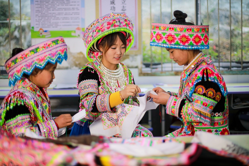 2025年12月16日，贵州省黔西市太来彝族苗族乡院子小学的学生在民间刺绣艺人（右二）的指导下学习刺绣技艺。.jpg