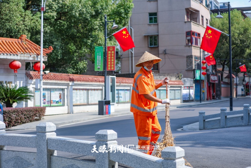 1036909-9月28日，印江县城，环卫工人在挂满五星红旗的街道上清扫路面，守护整洁街巷，静待国庆佳节。.JPG